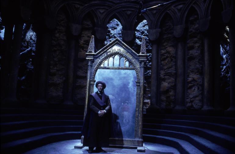 Harry Potter standing before the Mirror of Erised in Harry Potter and the Philosopher’s Stone, seeing his parents reflected.