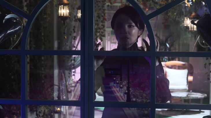 The Lady looks through a window longingly toward Nem in Kamen Rider Zeztz Episode 32 during an emotional separation scene
