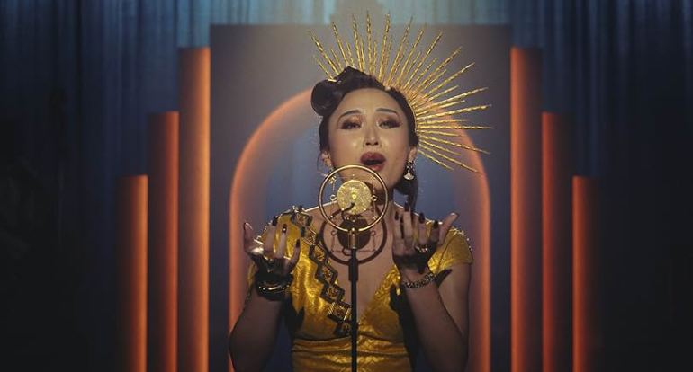Kat Hardy singing on stage beneath dramatic golden lighting in Spider Noir Episode 1.