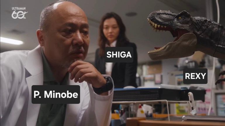 Professor Minobe studies a toy Tyrannosaurus rex while Shiga watches in Ultraman Teo Episode 3.