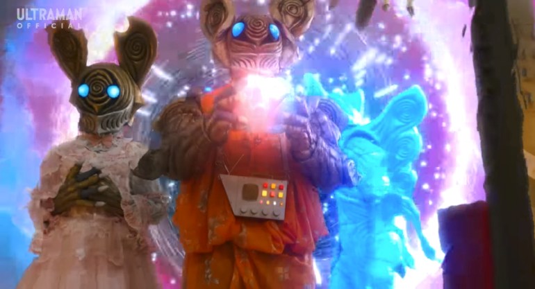Alien Barossa and his sister stand together as a glowing miniature Meteokaiju appears beside them during Ultraman Omega Episode 18.