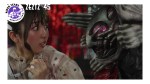 Nem stares wide-eyed at Oblivion Gore Nightmare, whose face is inches from hers, in a close-up confrontation with a red background.