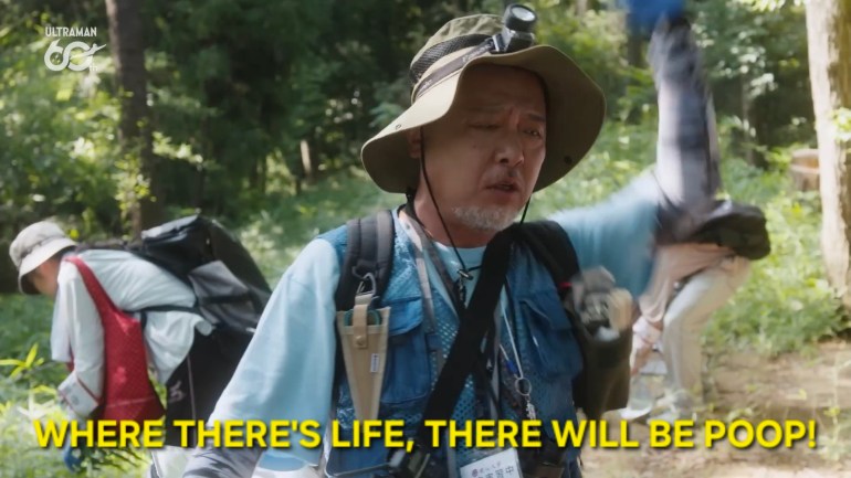 Professor Minobe gestures while declaring, "Where there's life, there will be poop!" during a forest investigation into the mysterious kaiju's biology.