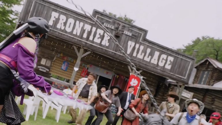 The purple Beast Hunter battles in front of Frontier Village, an Old West-style tourist town filled with modern visitors in Omegahorn Episode 1.