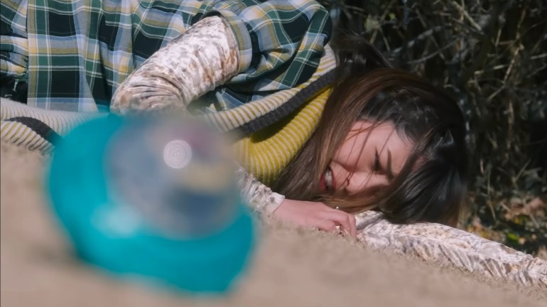 Nem lies injured on the ground while the blue Exdreamrise Capsem sits out of focus in the foreground.