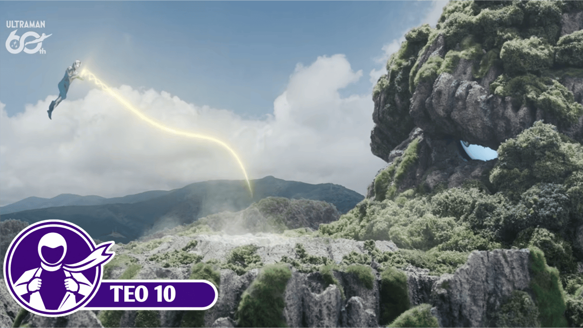 Ultraman Teo floats in the sky, firing a thin, glowing yellow beam toward the enormous, rocky, vegetation-covered face of Ozuyanushi on a mountainside.