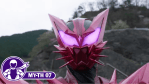 Close-up of Kamen Rider Maou's angular pink-and-red helmet, featuring glowing purple eyes, tall pointed ears, and sharp spikes around the mouth. A purple MY-TH 07 graphic appears in the lower-left corner.