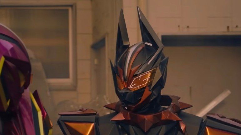 Close-up of Vanken in black and bronze armor with tall pointed ears, an orange targeting display over one eye, and a spiked collar-like neck piece.