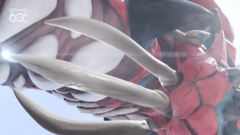 Close-up of giant Pucchi's red armored forelimb and several long, curved, pale claws, with portions of his red and black body visible behind them.